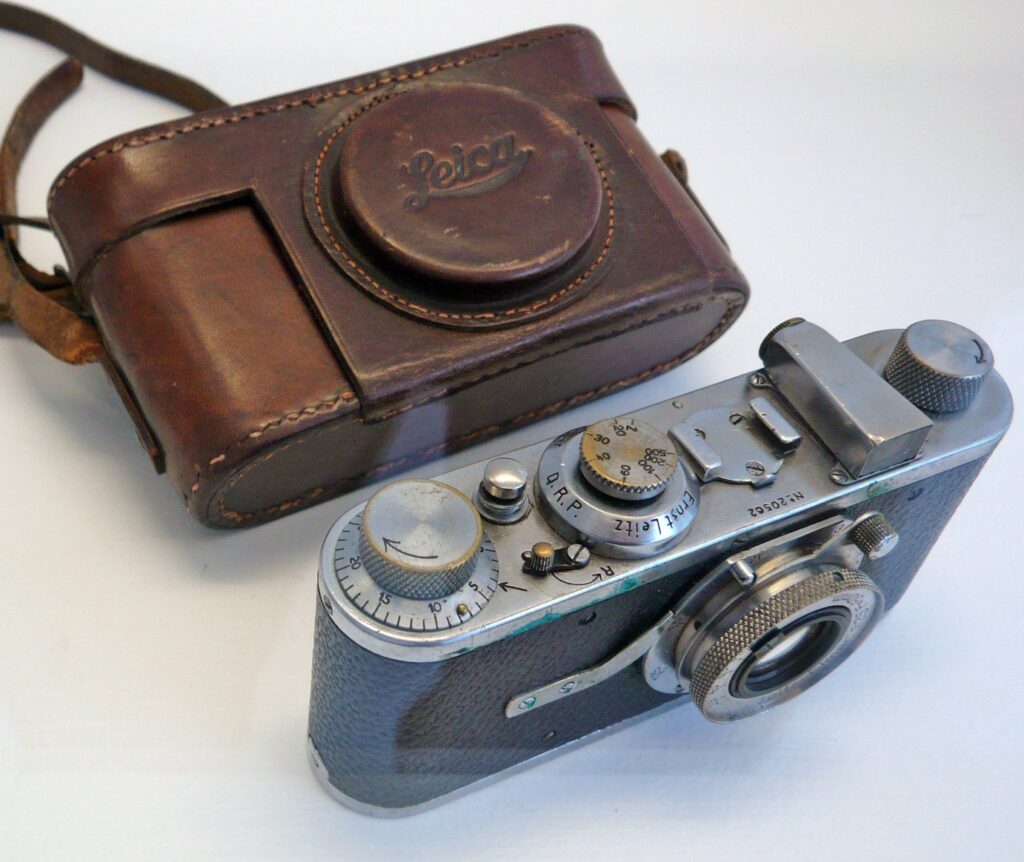Ancien appareil Leica argenté posé à côté de son étui en cuir